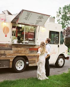 a man and woman standing in front of a food truck