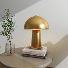 a gold lamp sitting on top of a table next to a vase with a plant