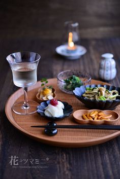 a wooden plate topped with food next to a wine glass and two glasses filled with liquid