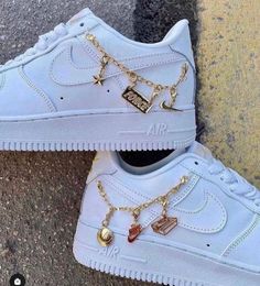 a pair of white nike air force sneakers with gold chains attached to the soles