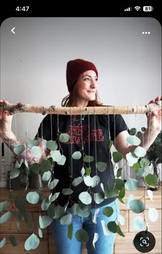 a woman holding up a piece of wood with leaves attached to it