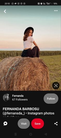 a woman sitting on top of a hay bale in the middle of a field