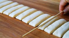 a person is cutting up some food on a wooden board with a toothpick