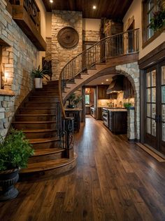 a large open floor plan with wood floors and stone walls, stairs leading up to the kitchen