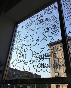 a window with graffiti written on it in front of a building and another building across the street