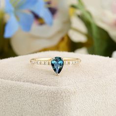 a blue heart shaped diamond ring sitting on top of a cushion