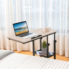 a laptop computer sitting on top of a wooden desk next to a window with curtains