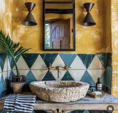 a bathroom sink sitting under a mirror next to a potted palm tree in front of it