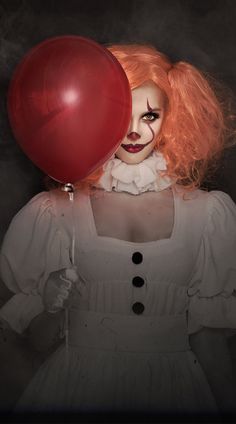 a creepy clown holding a red balloon in her hand and looking at the camera with an evil look on her face