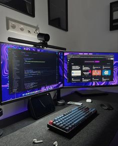 two computer monitors sitting on top of a desk with keyboard and mouse next to each other