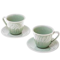 two green cups and saucers sitting next to each other on top of white plates