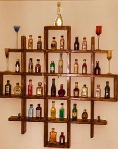 a wooden shelf filled with bottles and glasses on top of a wall next to a toilet