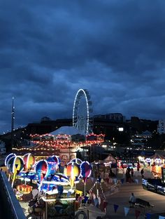 an amusement park is lit up at night with lights on and rides in the background