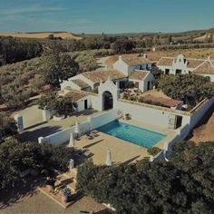 an aerial view of a house with a pool in the foreground and trees surrounding it