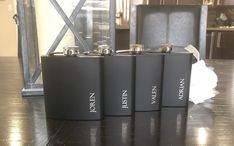 four black flasks sitting on top of a wooden table