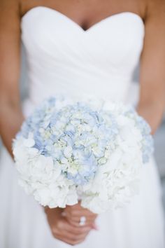 a bride holding a bouquet of white and blue flowers