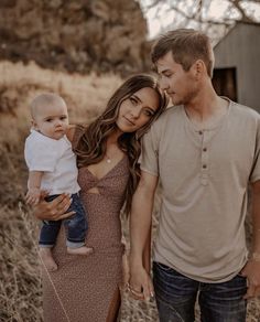 a man and woman holding a baby in their arms while standing next to each other