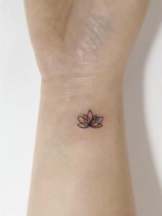 a small tattoo on the wrist of a woman's left arm with a lotus flower