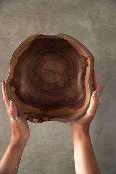 a person holding up a wooden bowl in their hands with one hand and the other