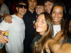 a group of young people standing next to each other at a party with drinks in their hands