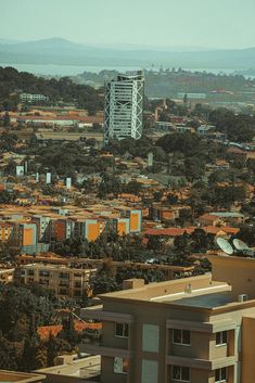 an aerial view of a city with tall buildings and lots of trees in the foreground