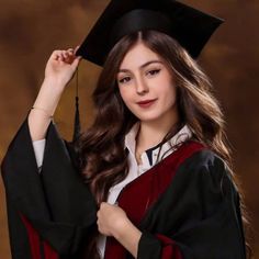 a young woman wearing a graduation cap and gown posing for a photo in front of a brown background