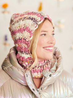 a woman in a silver jacket wearing a pink and white knitted beanie hat