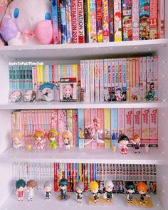 there are many books on the shelves with little dolls in front of them and a stuffed animal