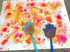 two blue spatulas sitting on top of a piece of paper covered in paint