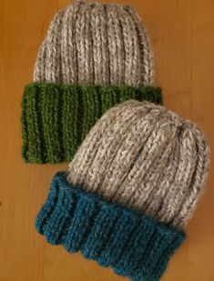 two knitted hats sitting on top of a wooden table