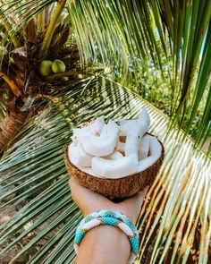 a person is holding a coconut with marshmallows on it in the palm tree