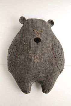 a stuffed bear hanging on the wall with it's head up and eyes closed