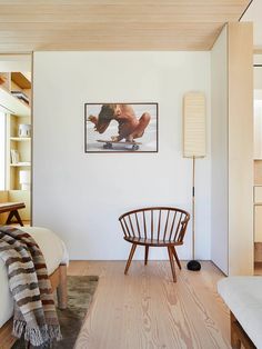 a bedroom with white walls and wood floors, including a chair in the foreground