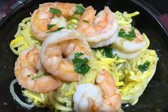 a black plate topped with pasta and shrimp