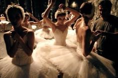 a group of people standing around each other in tutu skirts and dresses with their arms raised