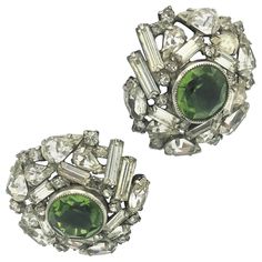 A pair of very nice and wearable ear clip with different shapes and cuts of rhinestones. In the middle there is a 1,5 cm large cut green rhinestone. He is made of silver metal and coms from the USA about 1940 years. Measurement: Diameter 3 cm, clip on, good Condition. All stones are set individually, not glued. Luxury Green Vintage Clip-on Earrings, Clear Rhinestones, Different Shapes, Clip On Earrings, Metallic Silver, Metallica, Jewelry Earrings, Thing 1, Engagement Rings