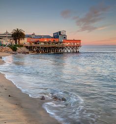 a beach with waves coming in to shore and buildings on the other side of the water