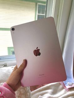 a person holding an apple ipad in their hand, with the screen partially covered by a pink sweater