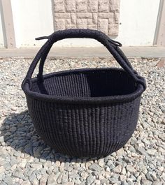 a black basket sitting on top of a gravel covered ground