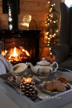 a tray with tea and cookies on it in front of a fireplace filled with lit candles