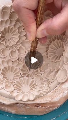 a person is working on an intricately designed cake with a wooden stick in their hand