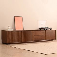 a record player sitting on top of a wooden cabinet next to a wall mounted speaker