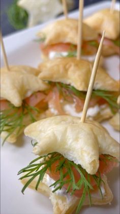 small appetizers with toothpicks are arranged on a white plate