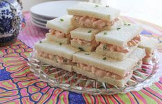 several sandwiches stacked on top of each other on a glass platter next to plates