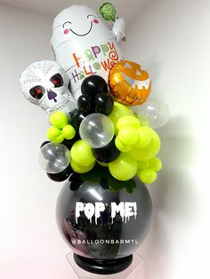 a black vase filled with lots of balloons and halloween decorations on top of a table