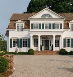 a large white house with green shutters on the front