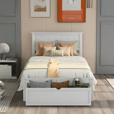 a white bed sitting in a bedroom on top of a hard wood floor next to two pictures