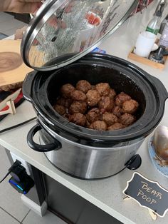 a pot full of meatballs sitting on top of a counter next to a sign