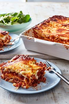 two plates with lasagna casserole on them, one has cheese and the other has greens