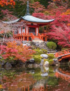 an orange pagoda in the middle of a pond surrounded by trees with red leaves on it